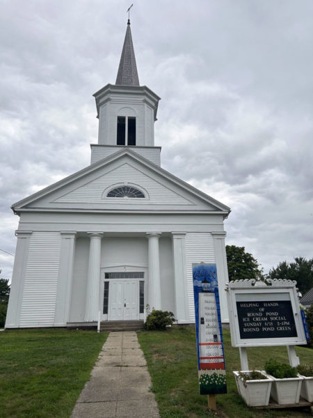 The Round Pond Meetinghouse stands against a cloudy sky on Tuesday, Aug. 20. The meetinghouse steeple, facade, and front porch were recently renovated to mitigate water damage. (Maia Zewert photo)