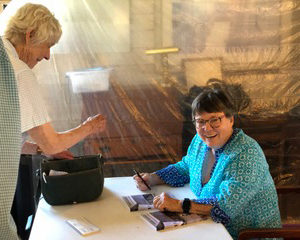 Memoirist Chris Chapman takes a break from autographing books after a reading on July 17 in Damariscotta. The event took place at the former Chapman Farm, now home to Inn Along the Way, which Chapman described as a magnificent manifestation of what her parents would have wanted for the farms future. (Sarah Masters photo)