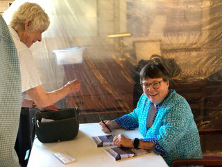 Memoirist Chris Chapman takes a break from autographing books after a reading on July 17 in Damariscotta. The event took place at the former Chapman Farm, now home to Inn Along the Way, which Chapman described as a magnificent manifestation of what her parents would have wanted for the farms future. (Sarah Masters photo)