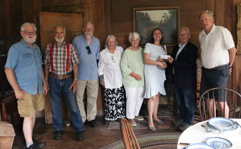 From left: Dave Probert, Chuck Vaughan, Greg Edwards, Perry Palmer, Robin Grant, Lincoln County Historical Association Executive Director Shannon Gilmore, Maine Antiques Dealers Association endowment fund chair Harry Hepburn, and Christopher Stanley stand in front of a landscape painting by Henry Cheever-Pratt in Dresden's Pownalborough Court House on Wednesday, July 31. The Maine Antiques Dealers Association donated $1,000 to the Lincoln County Historical Association to help cover the cost of the painting's restoration. (Piper Pavelich photo)