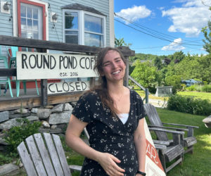 Emma McDowell, of Bristol, stands outside the building that houses Round Pond Coffee and The Common House wine bar. McDowell, who has traveled internationally as a teacher and advocate for agricultural and environmental justice, now works for a nonprofit supporting migrant workers in Maine, runs her own business selling fair-trade goods, creates her own art, and bartends at The Common House. (Molly Rains photo)