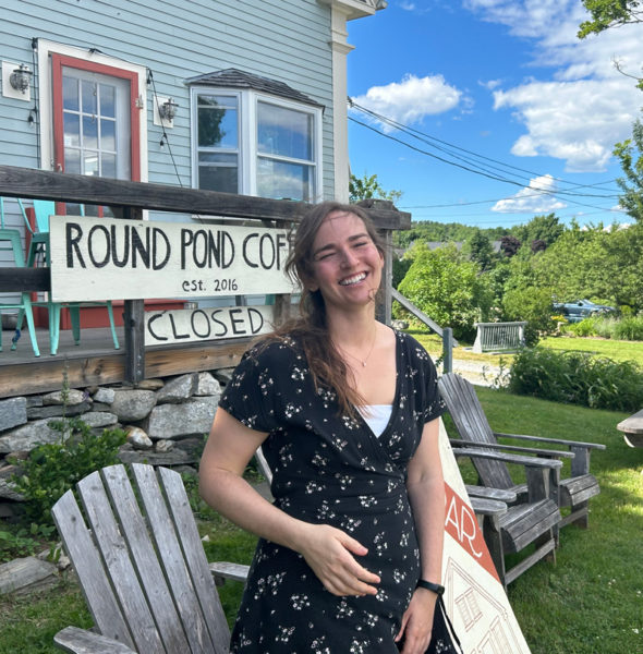 Emma McDowell, of Bristol, stands outside the building that houses Round Pond Coffee and The Common House wine bar. McDowell, who has traveled internationally as a teacher and advocate for agricultural and environmental justice, now works for a nonprofit supporting migrant workers in Maine, runs her own business selling fair-trade goods, creates her own art, and bartends at The Common House. (Molly Rains photo)