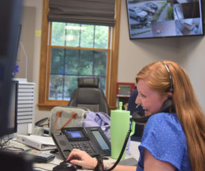 Rhiannon "Rhi" Hersey laughs at a joke told by fellow dispatcher Regan Pearce while on a nonemergency line on the phone at the Lincoln County Communications Center in Wiscasset on Thursday, July 25. Hersey, who is the most experienced of the three dispatchers on the shift, takes on the role of acting supervisor. (Nolan Wilkinson photo)