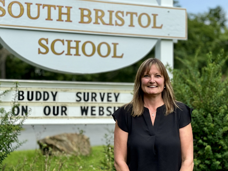 South Bristol Schools new principal, Laurie Stiles, stands in front of the schools sign on Friday, Aug. 16. Stiles said she looks forward to helping SBS continue forward in a good direction while developing and deepening the communitys connection with the school. (Johnathan Riley photo)