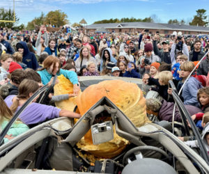 A crowd swarms around a car destroyed by a 1,000-pound pumpkin at Great Salt Bay Community School in Damariscotta on Sunday, Oct. 13. This year marked the pumpkin drops return to the Damariscotta Pumpkinfest and Regatta schedule for the first time since 2019. (Johnathan Riley photo)