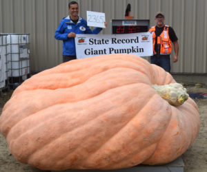 WGME CBS 13 Chief Meteorologist Charlie Lopresti (left) holds a banner declaring him the new state record holder for largest pumpkin at the Damariscotta Pumpkinfest & Regatta Great Pumpkin Commonwealth weigh-off at Louis Doe Home Center in Newcastle on Sunday, Oct. 6. Lopresti's 2,365.5-pound pumpkin smashed the old state record of 2,121.5 pounds set in 2021 by Edwin Pierpont, of Jefferson. (Nolan Wilkinson photo)