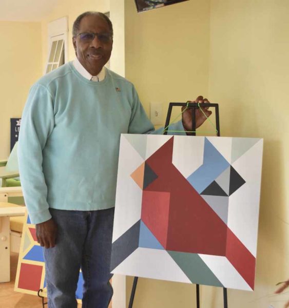 Edgecomb artist Leeroy Gandy stands with a barn quilt he painted, featuring a cardinal and blue jay. Gandy, a lifelong artist and mathematician, said he takes inspiration from birds and the natural beauty of the Midcoast for his barn quilts and other artistic pursuits. (Molly Rains photo)