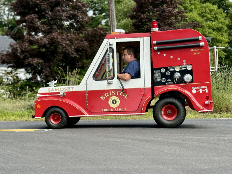 A firefighter drives a miniature fire truck in the Olde Bristol Day parade on Aug. 10 in New Harbor. The vehicle was constructed by Michael Morrison. (Johnathan Riley photo)