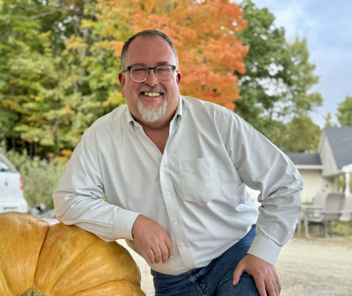 Damariscotta Pumpkinfest and Regatta Executive Director Jed Weiss leans on a larger than normal pumpkin on Friday, Oct. 4 in Newcastle. When hes not organizing Damariscottas largest festival, hes working at Colby and Gale in Damariscotta in service dispatch or restoring cast iron cookware. Weiss formerly co-owned King Eiders Pub in Damariscotta where he was also the bar manager. (Johnathan Riley photo)