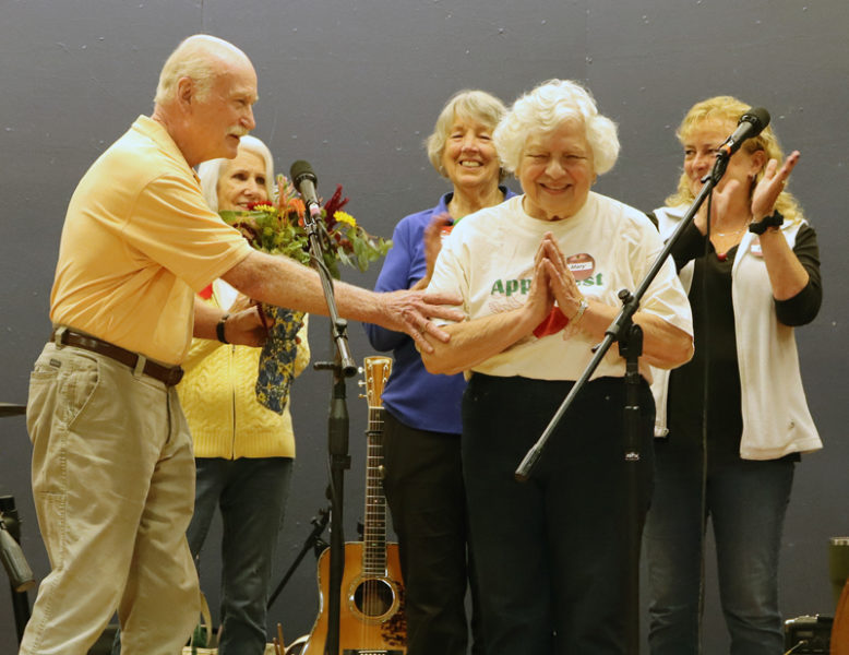 Nobleboro Historical Society President Mary Sheldon (right) expresses gratitude to attendees of Nobleboro's 19th annual AppleFest on Saturday, Oct. 5 as Dewey Meteer (left) hands her a bouquet of flowers. Sheldon was recognized for her nearly 20 years of service to the historical society during AppleFest. (Piper Pavelich photo)