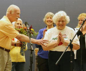 Nobleboro Historical Society President Mary Sheldon (right) expresses gratitude to attendees of Nobleboro's 19th annual AppleFest on Saturday, Oct. 5 as Dewey Meteer (left) hands her a bouquet of flowers. Sheldon was recognized for her nearly 20 years of service to the historical society during AppleFest. (Piper Pavelich photo)