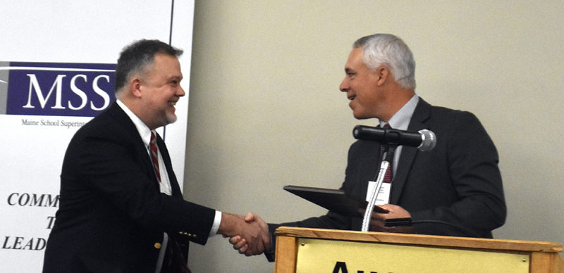 RSU 12 Superintendent Howard Tuttle (left) accepts the Maine Superintendent of the Year Award from last years winner, Jonathan Moody, at the Augusta Civic Center on Wednesday, Oct. 23. Public schools  the American public school system  is like no other in the world. Its the backbone of our democracy, Tuttle said. (Molly Rains photo)