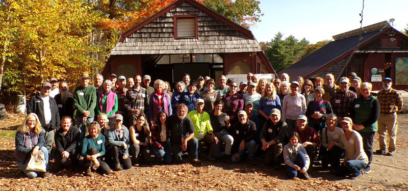 Friends old and new, supporters, associates, and honored guests gather at Hidden Valley Farm in Whitefield for the official presentation of the 2024 New England Leopold Conservation Award to David "Traci" Moskowitz and Bambi Jones on Saturday, Oct. 19. Jones, who is kneeling in the center of the group with Moskowitz, suggested a group picture would better celebrate the award, underscoring the value and power of community. (Sherwood Olin photo)