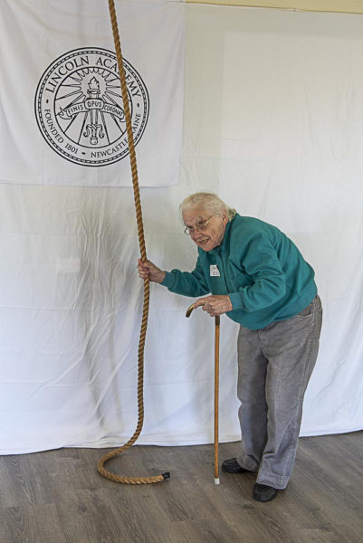 Arlene Cole, who repaired the bell in 1996, is the first to ring the newly refurbished bell from its new pull in the library annex of Lincoln Academy. (Photo courtesy Lincoln Academy)