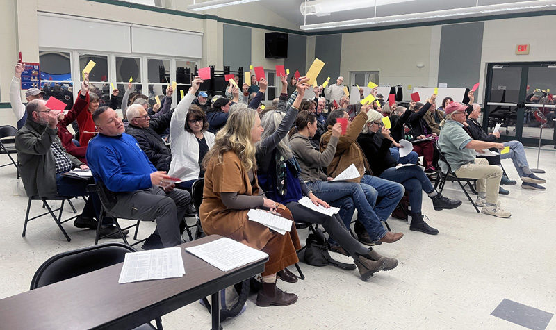 Voters raise their hands in opposition of AOS 93's proposed $1.2 million budget for the 2026 fiscal year during a meeting at Great Salt Bay Community School in Damariscotta the evening of Wednesday, Dec. 18. While the special education and student and staff support sections of the budget were approved, voters turned down the $761,503.22 system administration budget, which houses salaries and other expenditures associated with AOS 93's central office. (Piper Pavelich photo)