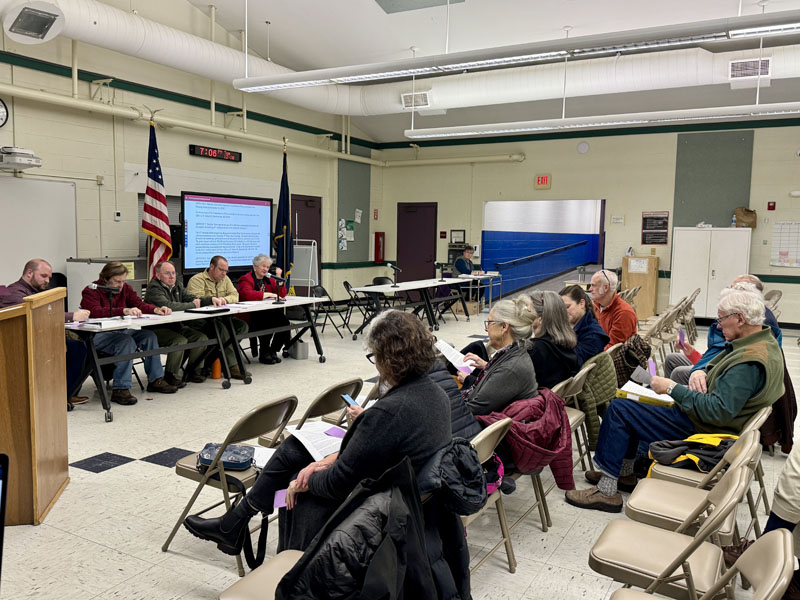 Damariscotta residents sit in the Great Salt Bay Community School cafeteria during a special town meeting on Tuesday, Dec. 10. Voters approved all articles on the warrant, which included allocating funds for electric vehicle chargers in the municipal back parking lot, amendments to the shoreland zoning ordinance, and the acceptance of a new comprehensive plan. (Johnathan Riley photo)