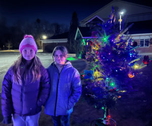 Edgecomb Eddy School fourth graders Isabel Wallace (left) and Llireva Blagdon stand beside the tree their class decorated as part of the town's Charlie Brown Christmas tree tradition. "It was fun, but a little crazy" to work on the tree as a class, said Blagdon. (Molly Rains photo)