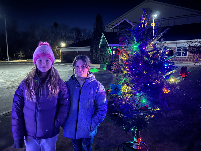 Edgecomb Eddy School fourth graders Isabel Wallace (left) and Llireva Blagdon stand beside the tree their class decorated as part of the town's Charlie Brown Christmas tree tradition. "It was fun, but a little crazy" to work on the tree as a class, said Blagdon. (Molly Rains photo)