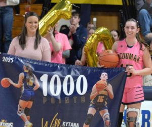 Medomak Valley senior Kytana Williamson and coach Lindsay Vinal hold a banner in honor of Williamsons 1,000th career point, which she scored during a home game on Monday, Jan. 20. (Paula Roberts photo)