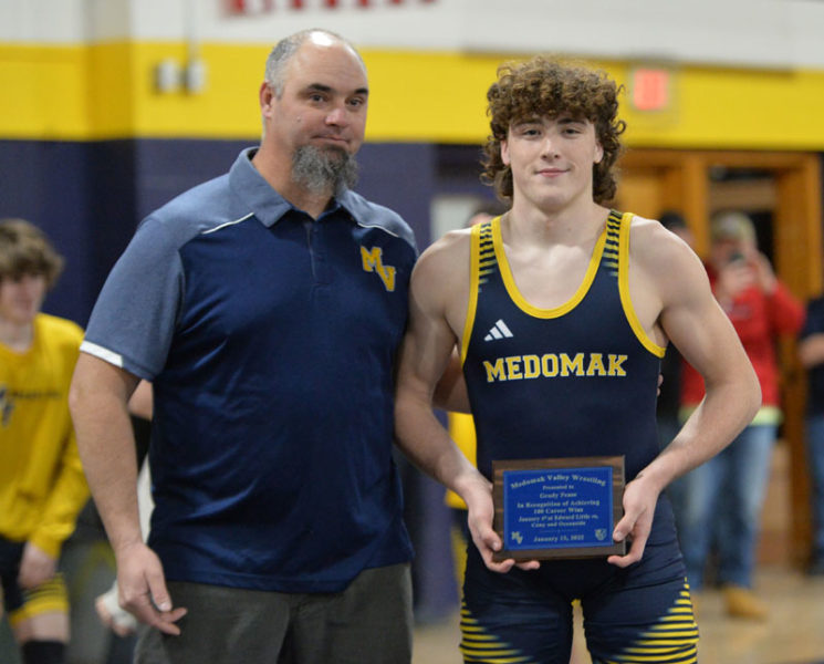 Medomak Valley wrestling coach Jeb Harris presents junior Grady Pease with a plaque recognizing him for his 100th career win. Pease earned the win on Jan. 4. (Paula Roberts photo)