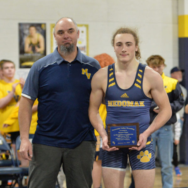 Medomak Valley wrestling coach Jeb Harris presents junior Shamus Pease with a plaque in honor his 100th career win, which Pease earned on Jan. 8. (Paula Roberts photo)