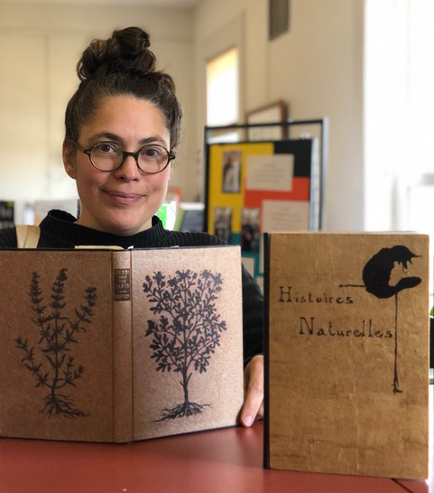 Whitefield book binder Celine Lombardi poses with two of her sample books that demonstrate her hand-cut leather details at the Whitefield Library on Friday, April 4 in advance of her solo show. (Sarah Masters photo)