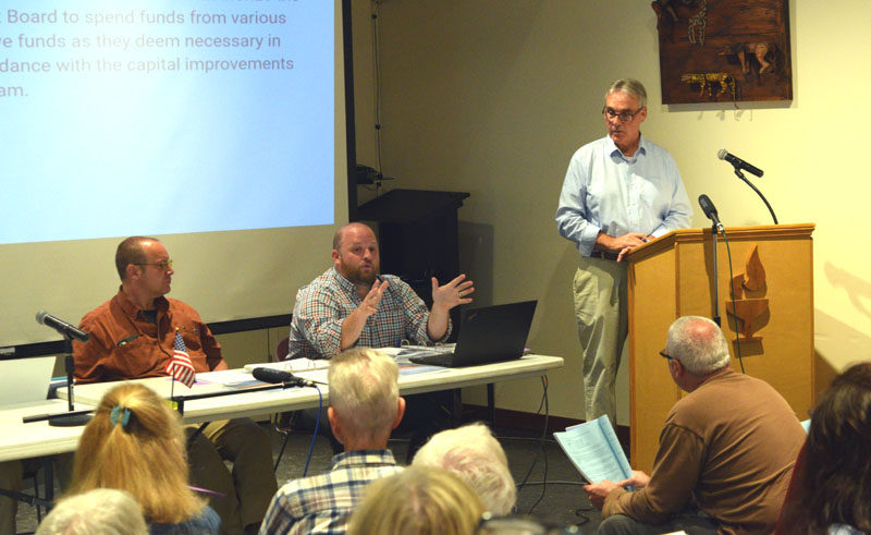 Damariscotta Town Manager Andy Dorr (center) explains a budgetary article relating to capital improvement funds as select board Chair Daryl Fraser (left) and meeting moderator Jim Cosgrove look on during the annual town meeting on Wednesday, June 11 at Skidompha Public Library in Damariscotta. (Ali Juell photo)