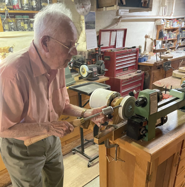 Tom Raymond sharpens a bowl gouge in his basement workshop in Damariscotta. The bowl gouge is the most important chisel in his toolbox, Raymond said. He will frequently begin working with three sharpened gouges so he can work uninterrupted when one chisel dulls. (Sherwood Olin photo)