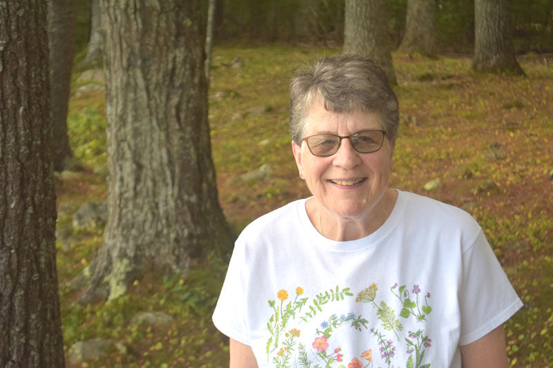 Joan Jackson smiles among pine trees on the shore of Damariscotta Lake. During her childhood in Jefferson, outdoor fun revolved around the lake, which Jackson loves deeply to this day, she said. (Molly Rains photo)