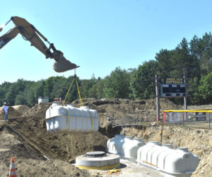 A crane lifts a septic system tank into place behind Medomak Valley High School the morning of Wednesday, Aug. 13. The Fuji Clean system, which replaces the schools failed system, was chosen for its small footprint relative to other systems that could not fit in the limited space available at the high school, according to RSU 40 Facilities Director Brian Race. (Molly Rains photo)