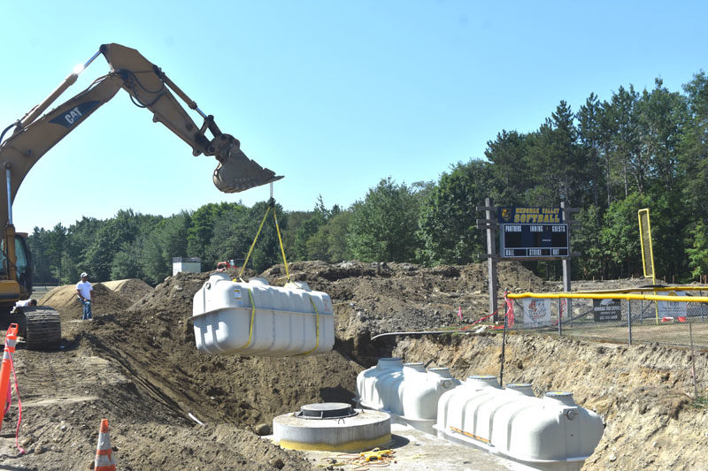 A crane lifts a septic system tank into place behind Medomak Valley High School the morning of Wednesday, Aug. 13. The Fuji Clean system, which replaces the schools failed system, was chosen for its small footprint relative to other systems that could not fit in the limited space available at the high school, according to RSU 40 Facilities Director Brian Race. (Molly Rains photo)
