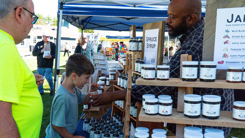 An attendee of the 2024 Maine Needham Festival samples jam from Pembroke-based Pen & Cob Farm. (Photo courtesy Drew Soucy Media)