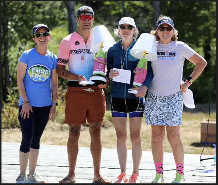 Pemaquid Beach Triathlon co-organizers Hannah McGhee (left) and Carla McKay (right) present buoy lamp prizes to race winners August Avantaggio and Allison Dimatteo on Sunday, Aug. 24. Avantaggio, 39, of Damariscotta, was the overall winner with a time of 1:14:12 and Dimatteo, 56, of Saco, was the top female racer and seventh overall with a time of 1:20:00. (Photo courtesy of Kris Christine)