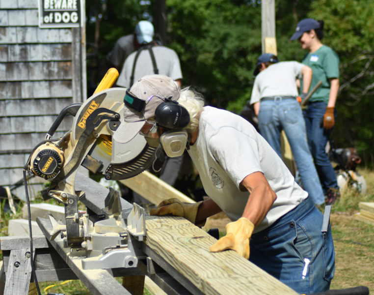 Community Housing Improvement Project Community Cares Day volunteer Sarah Highland cuts a pressure-treated board to length for a ramp volunteers were building for a mobility-challenged homeowner in Whitefield. On Saturday, Sept. 13, Highland's team built and installed the ramp and raised the level of the deck, allowing a wheelchair to smoothly roll over the foyer into the residence. (Sherwood Olin photo)