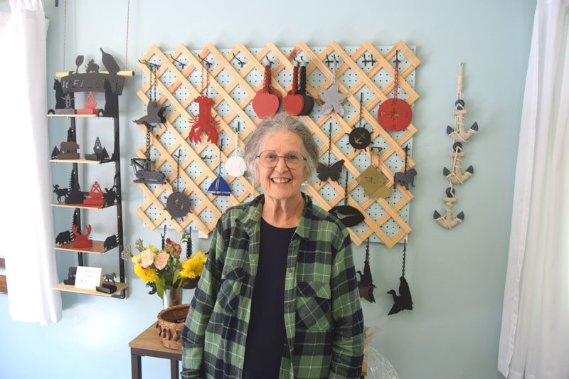 Peggy Davis, who bought North Country Wind Bells with her husband Ron Davis in 2024, stands in front of the kind of windcatchers that prompted them to buy the business. When they lost the windcatcher on their Nantucket buoy bell and went to the showroom to replace it, they had no idea the trip would turn into a new business venture. (Christina Wallace photo)
