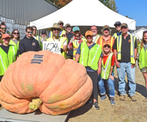 A crew of volunteers stands behind this year's heaviest pumpkin, which was grown by Elroy Morgan, after the professional weigh-off on Sunday, Oct. 5 in Newcastle. Executive Director Jed Weiss said Damariscotta Pumpkinfest and Regatta would not be possible with the hundreds of volunteers involved. (Ali Juell photo)