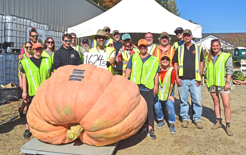 A crew of volunteers stands behind this year's heaviest pumpkin, which was grown by Elroy Morgan, after the professional weigh-off on Sunday, Oct. 5 in Newcastle. Executive Director Jed Weiss said Damariscotta Pumpkinfest and Regatta would not be possible with the hundreds of volunteers involved. (Ali Juell photo)