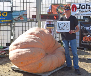 Elroy Morgan, of Charleston, stands next to his winning 1,624.5-pound pumpkin during the Great Pumpkin Commonwealth Weigh-Off at Louis Doe Home Center in Newcastle on Sunday, Oct. 5. In addition to growing the largest giant pumpkin, Morgan broke the long gourd state record at the event. (Ali Juell photo)