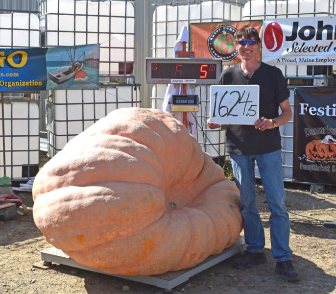 Elroy Morgan, of Charleston, stands next to his winning 1,624.5-pound pumpkin during the Great Pumpkin Commonwealth Weigh-Off at Louis Doe Home Center in Newcastle on Sunday, Oct. 5. In addition to growing the largest giant pumpkin, Morgan broke the long gourd state record at the event. (Ali Juell photo)