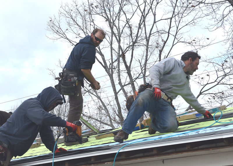 Scott Eastmen (left), RSU 40 Board of Directors member Timothy Wood (center), and Garret Hayden repair the roof of the building that houses the world-renowned Heirloom Seed Vault at Medomak Valley High School on Friday, Nov. 21. (Claire Taylor photo)