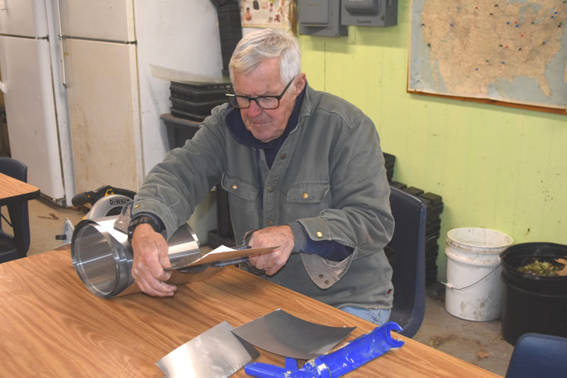 Neil Lash, founder of the Heirloom Seed Project at Medomak Valley High School, cuts step flashing for the roof during volunteer repair efforts on Friday, Nov. 21. Lash, who is now retired, said he was  "very, very, pleased" with the endeavor since the roof has been in "dire needs." (Claire Taylor photo)