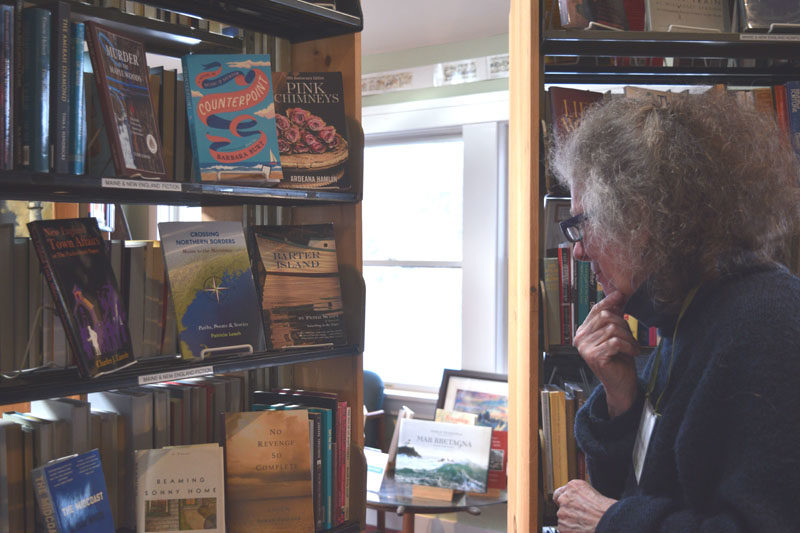 Skidompha Secondhand Book Shop volunteer Jennifer Bunting studies a display of books on Monday, Nov. 17. Bunting said she enjoys volunteering alongside her friend Janice Lindsay. (Ali Juell photo)