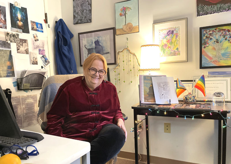 Ellie Busby cracks a smile while telling a story in her office at Mobius Inc. in Damariscotta. A mockup of the cover of her forthcoming book of poetry, Just North of Ordinary Tides, is visible on the table to her left. (Sherwood Olin photo)
