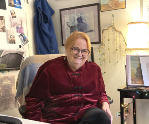 Ellie Busby cracks a smile while telling a story in her office at Mobius Inc. in Damariscotta. A mockup of the cover of her forthcoming book of poetry, Just North of Ordinary Tides, is visible on the table to her left. (Sherwood Olin photo)