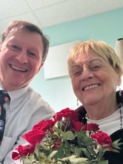 Dr. John McCormick poses for a selfie with his last patient, Joann Ames, on his last day of work before retirement on Tuesday, Dec. 16. McCormick gave Ames a pot of red roses in commemoration of her status as his final patient. (Photo courtesy Joann Ames)