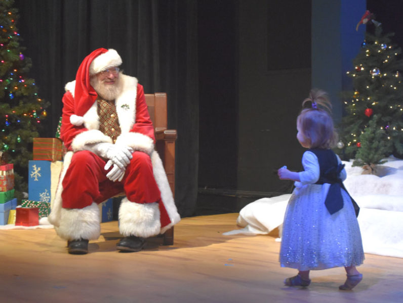 Two-year-old Hazel Woodard, of Damariscotta, runs across the Lincoln Theater stage to meet Santa Claus during his appearance on Saturday, Nov. 29. Santa's visit kicked off the day long Villages of Light Festival. Other festival events included a screening of the 2004 classic "The Polar Express," crafts the Skidompha Public Library, and the Villages of Lights parade. (Claire Taylor photo)
