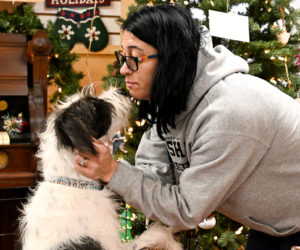 Maria Lowe of Bristol gets a kiss from Snoopy during The Maine Dog Rescues holiday pop-up event at the Good Things Thrift and Craft Shop in Waldoboro on Saturday, Dec. 20. I am definitely a dog lover, Lowe said. I just want to take them all home. (Bisi Cameron Yee photo)