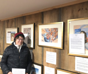 Waldoboro artist Jean Kigel poses in her Back Cove gallery next Constellation of Drones, one of 11 portraits she created to capture various current immigrant experiences in the United States and beyond in Displacement: Immigrant Portraits. The exhibition is on display through January at Skidompha Public Library in Damariscotta. (Sarah Masters photo)