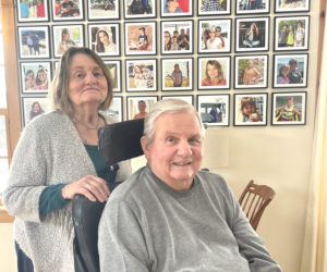 Rosie and Paul Kelsey Sr. pose in front of photo array of family members in the living room of their Walpole home. The couple met as teenagers while roller skating in Pemaquid and married in 1967, just after Paul Kelsey returned from serving in the Army in Vietnam. (Sherwood Olin photo)