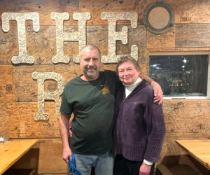 Steve and Karen Brackett, proprietors of King Ro Market and The Ro in Round Pond, stand in front of a wall in the pub autographed by hundreds of patrons. The couple said they are touched and appreciative of the all support they have been received since Steve's diagnosis with amyotrophic lateral sclerosis, or ALS, in August 2025. Fundraising efforts have raised more than $50,000 to date. (Sherwood Olin photo)